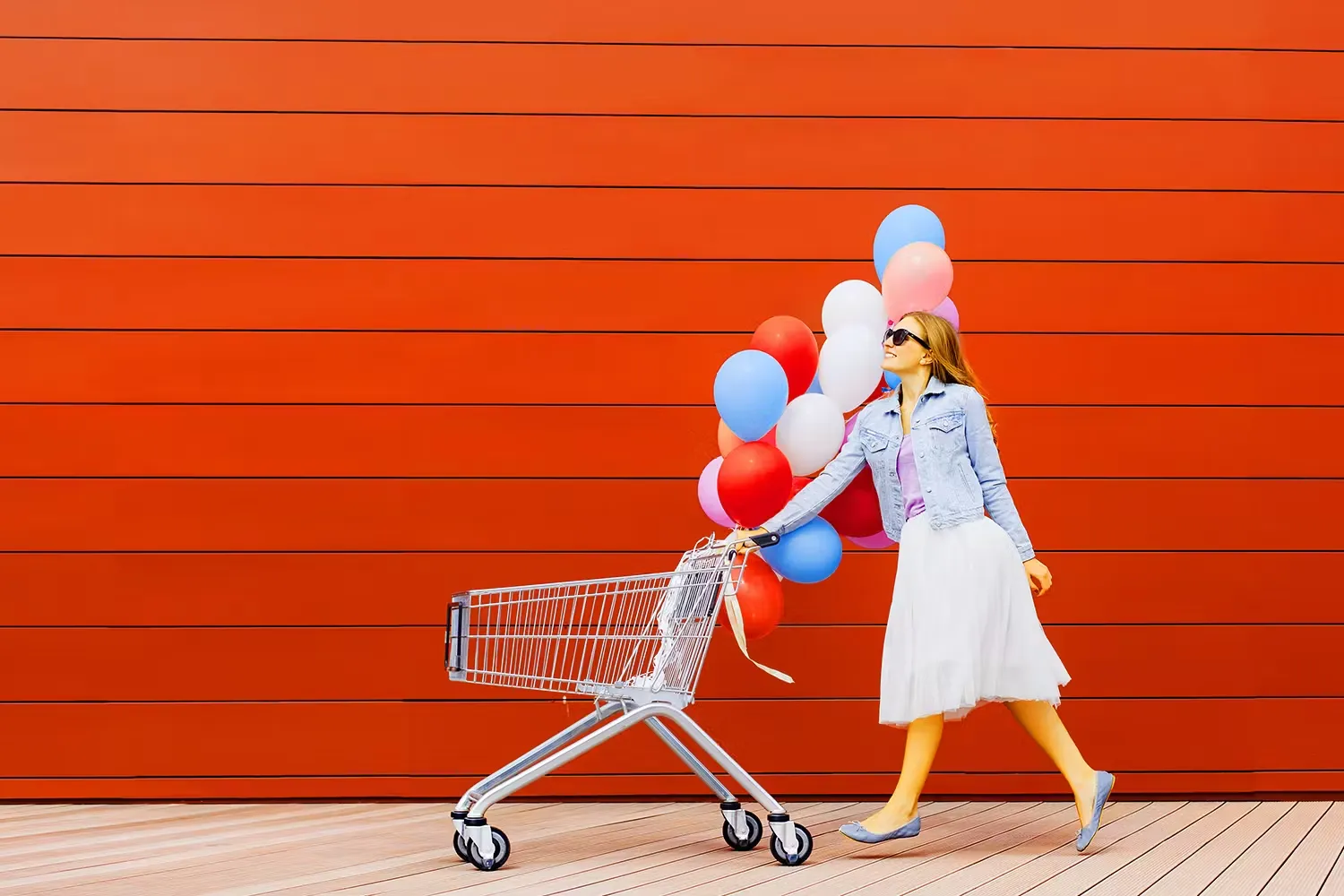 Woman pushing shopping cart with balloons on it